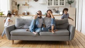 photo de parents dans un canapé qui semblent fatigués par les enfants qui courent autour d'eux