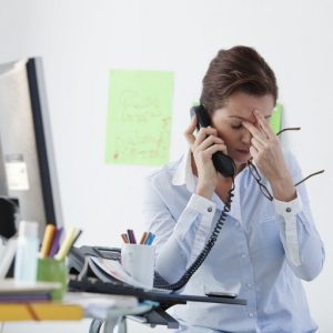 photo d'une femme au téléphone sur son lieu de travail qui semble en souffrance