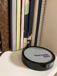 photo d'un dispositif anti-ondes, le Vernada Odo présenté sur une étagère devant des livres